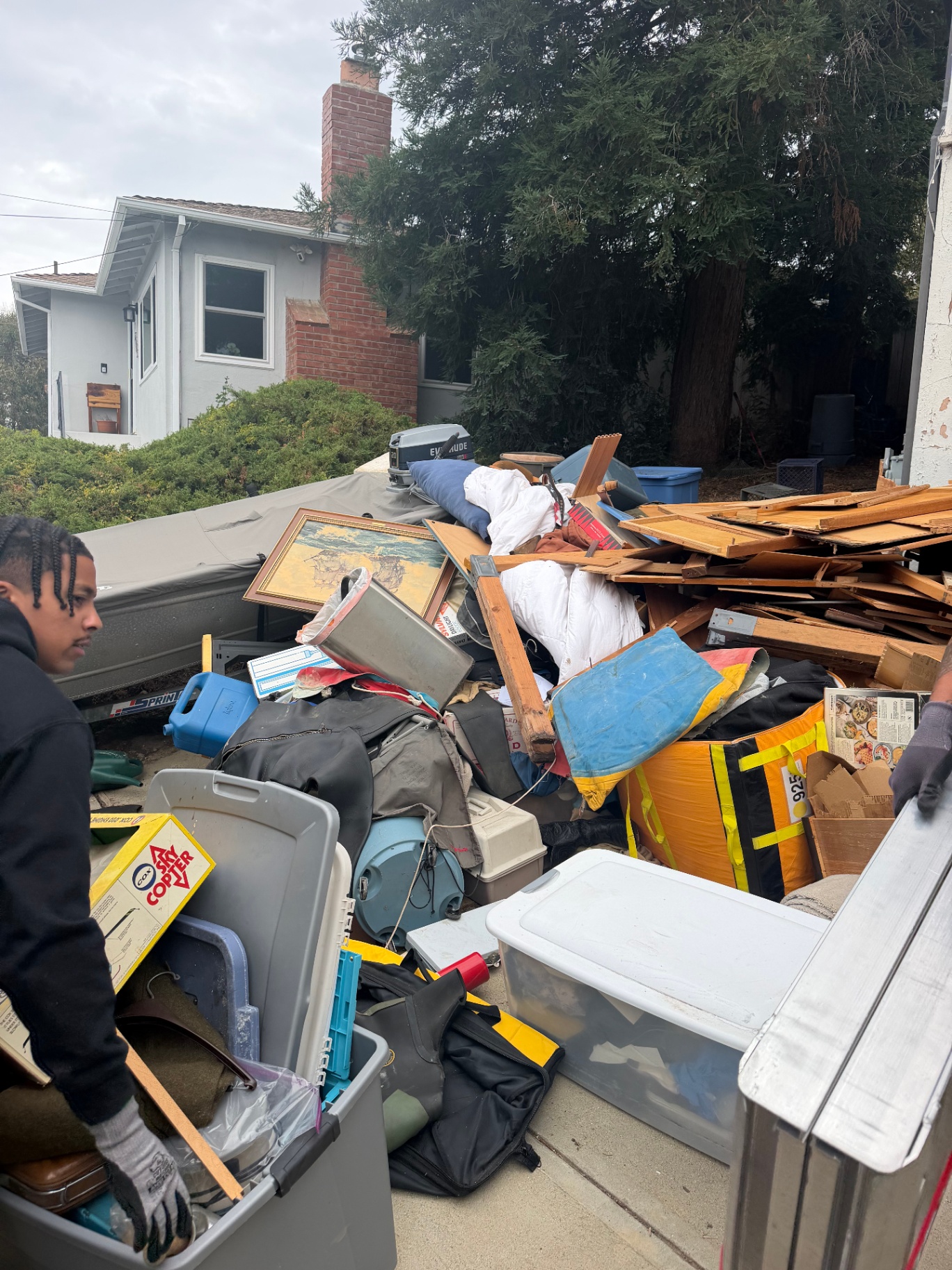 Greer Hauling crew member clearing junk from a Bay Area driveway into the hauling trailer